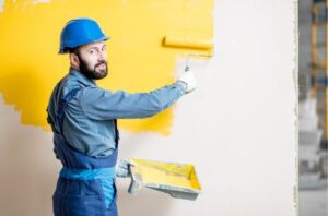 A man painting interior wall with yellow color